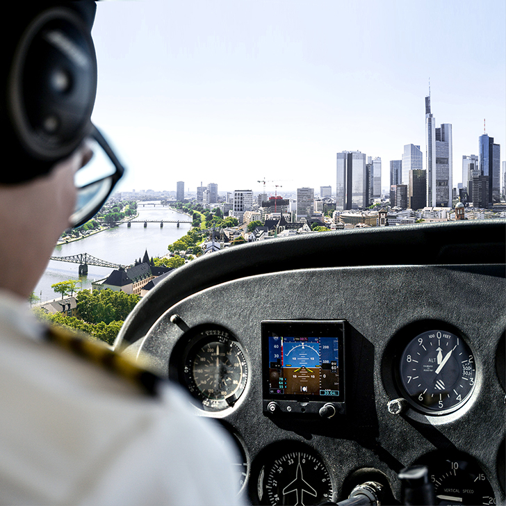 Pilot im Cockpit steuert Flugzeug über der Skyline von Frankfurt am Main – visuelle Meta-pher für Risikomanagement in Banken.